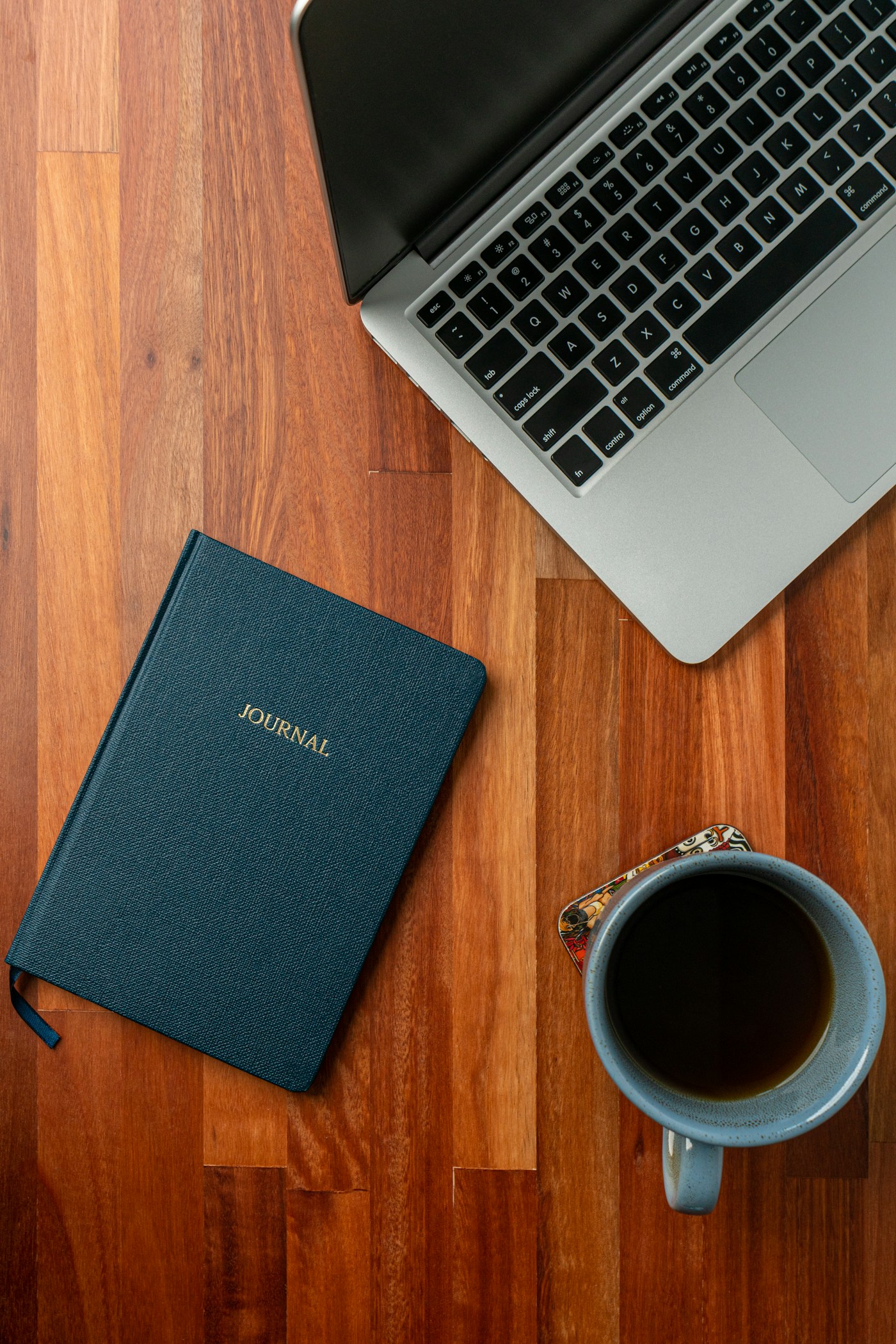 Journal, laptop, and coffee on a desk